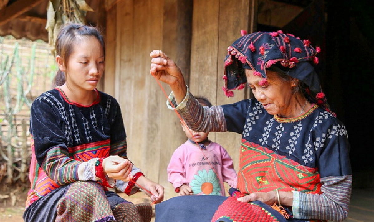 Bên hiên nhà sàn, các bà, các mẹ vẫn đang tiếp tục giữ gìn và truyền dạy nghề thêu thủ công 
cho thế hệ trẻ