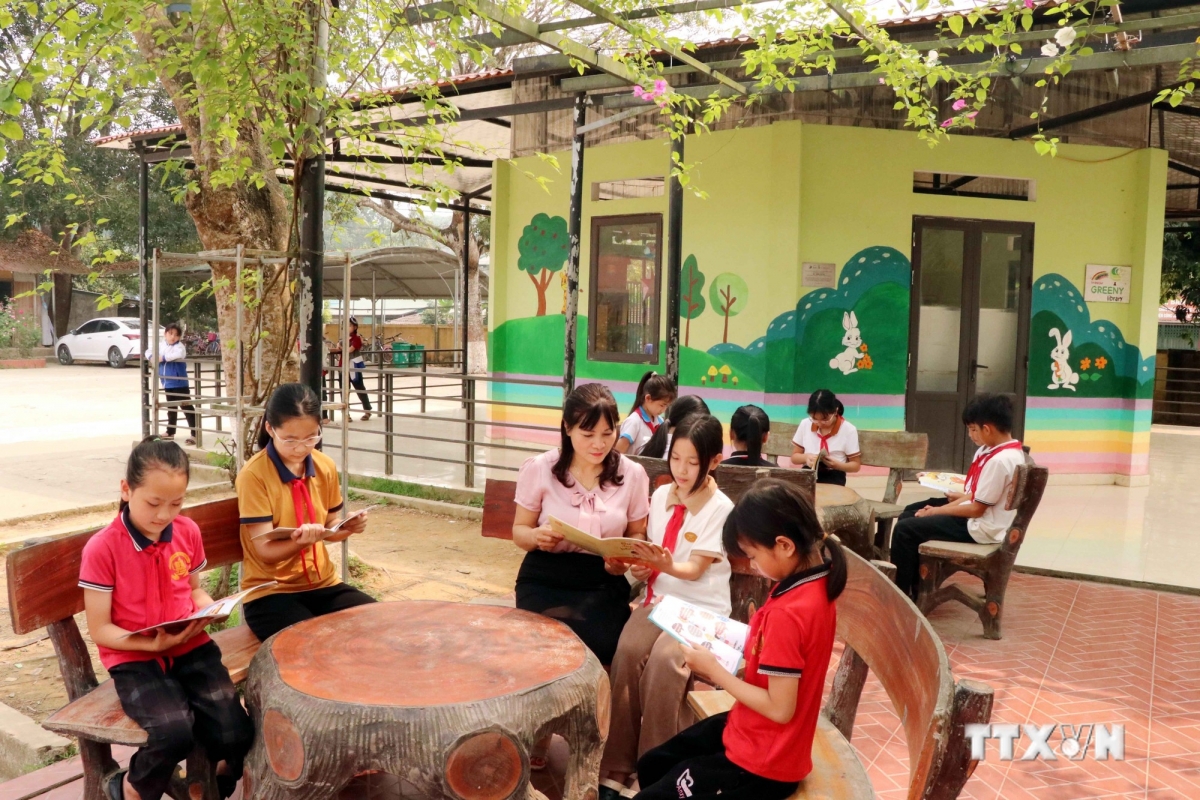 Học sinh đọc sách tại khu vực đọc ngoài trời của Thư viện Cầu vồng, Trưởng Tiểu học Tứ Quận, huyện Yên Sơn. Ảnh: Quang Cường – TTXVN